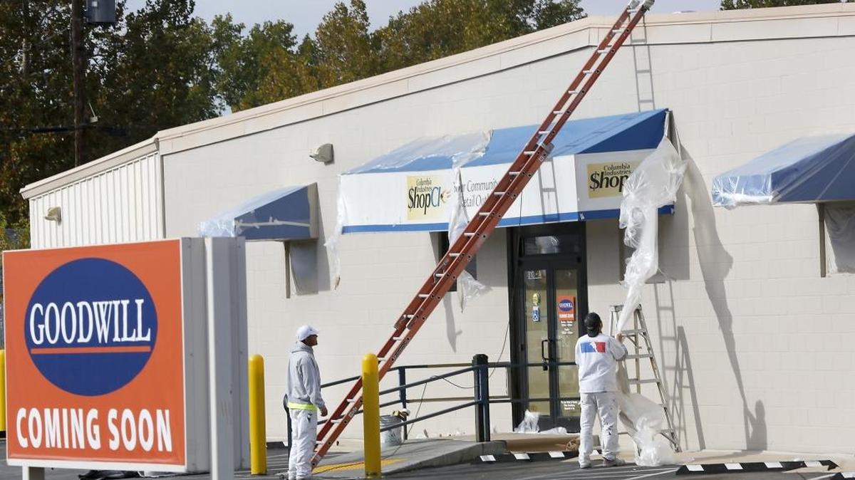 Horizon Construction employees Angel Ramirez, left, and Victor Lopez work Tuesday afternoon to remove protective plastic sheeting covering the awnings during repainting of the former ShopCI store on South Dayton Street in Kennewick. The thrift store closed Sept. 18 and will reopen later this year as a Goodwill Industries store. Columbia Industries clients were offered training opportunities within the Goodwill network, according to the agency.