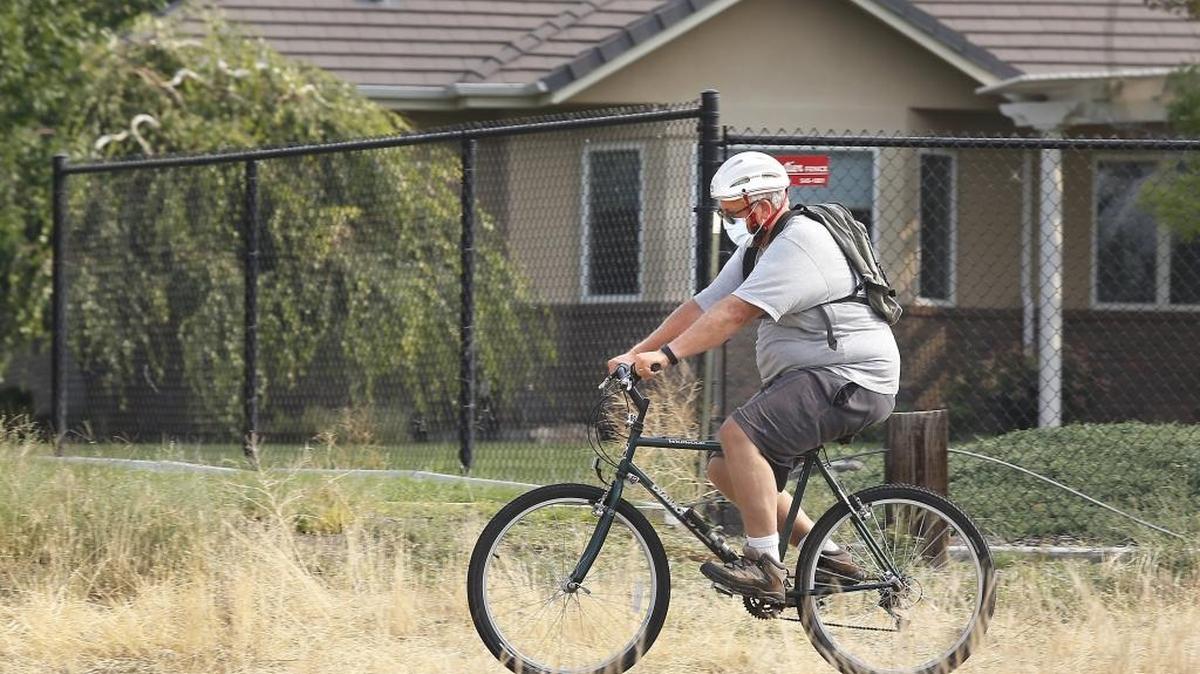 This bicyclist heeds the warnings of local health officials to wear a particulate mask while pedaling Friday in west Pasco in the smoky conditions. Poor air quality has lingered in the Mid-Columbia region as smoke from Northwest wildfires settled across the state. The air quality alert issued by the State Department of Ecology remains in effect until noon Saturday. Temperatures also are expected to drop a few degrees into the high 90s, then into the 80s on Sunday and Monday, said the National Weather Service.