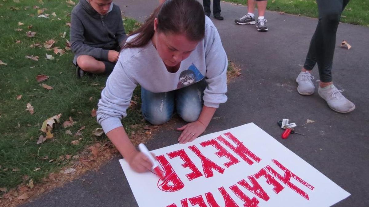A participant in Sunday’s candlelight vigil prepares a sign to remember Heather Heyer, the woman killed during the Charlottesville protests.