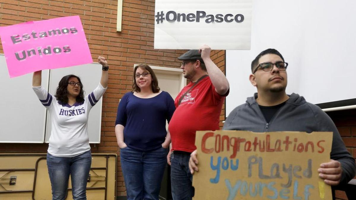 Pasco residents, from left, Cynthia Ledesma, Loren Polk, Matthew Polk and Jamie Torres hold signs Tuesday during a Kennewick City Council meeting. More than 100 gathered during the meeting in reaction to Councilman Bob Parks’ private Facebook postings disparaging Pasco, Yakima and Latinos.