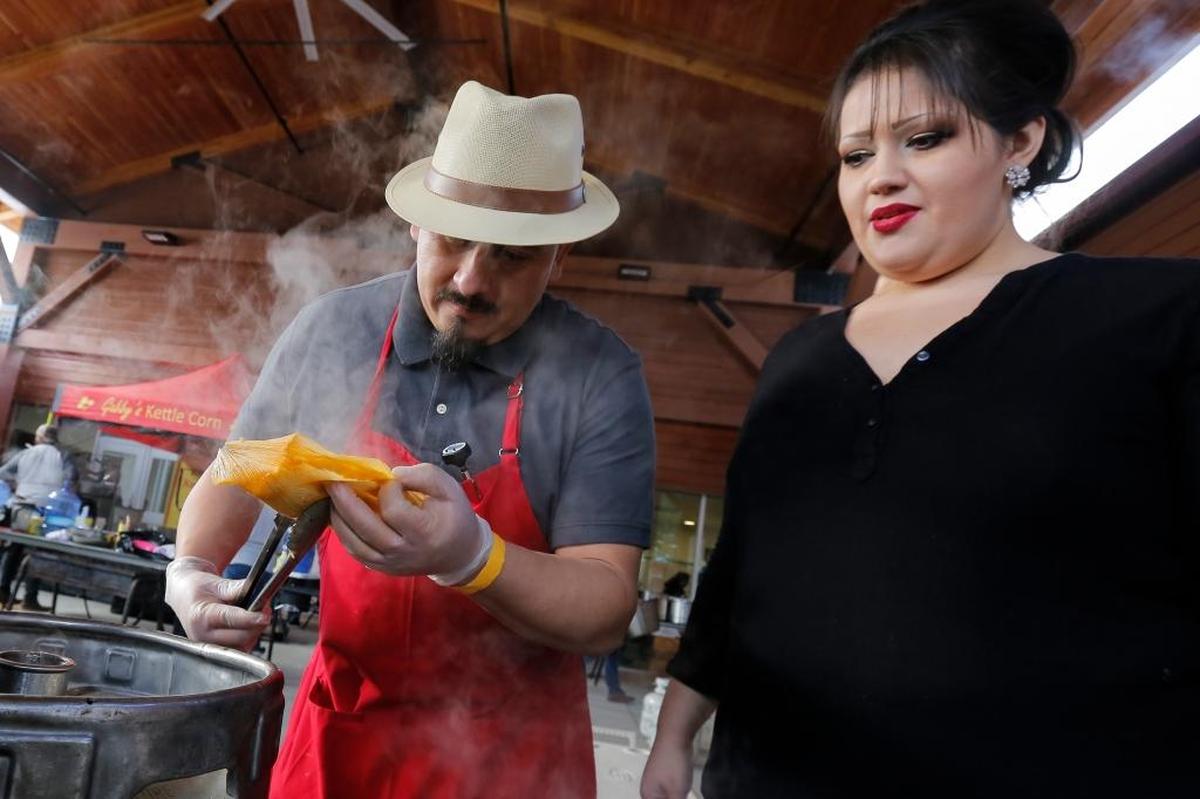 Ivan Alamilla opens up a tamale after it was steamed to make sure it is cooked as Sonia Alamilla watches.