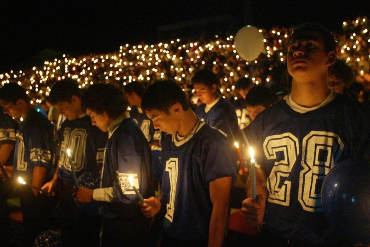 Carlos Mendoza, right, prays alongside his Ki-Be High School football teammates at a memorial service for Bob Mars in September 2004.