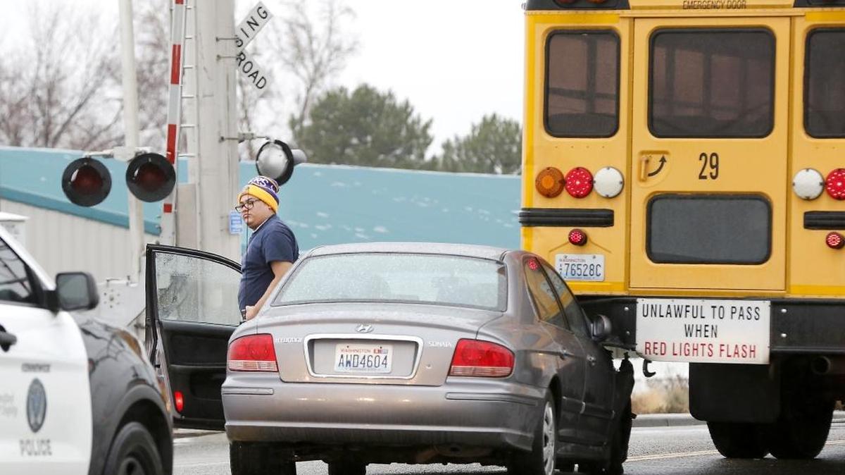 Krystopher Casas gets out the Hyundai Sonata he was driving Tuesday when he rear-ended a school bus stopped for the railroad tracks on North Kellogg Street in Kennewick. No students were on the bus and no one was injured during the crash. The bus, driven by Michael Smith, has just left the Kennewick School District's bus barn and was on its way to pick up students. Casas was cited for following too close, police said.