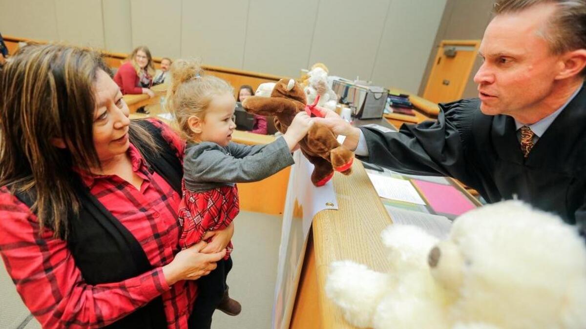 Evangelina Sanchez holds her daughter, Fernanda Sanchez, 3, as she picks a stuffed animal from Judge Alex Ekstrom during the celebration of National Adoption Day at Benton-Franklin Superior Court on Friday at the Benton County Justice Center. After the adoption ceremony, it is a tradition that each child gets to pick a stuffed animal. The stuffed animals were donated by the local bar association.