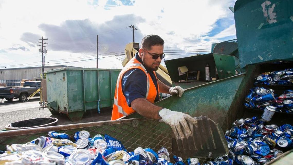 Eddie Lopez, a supervisor at Central Washington Recycling, pushes cans through a machine to be compressed Friday in Yakima.