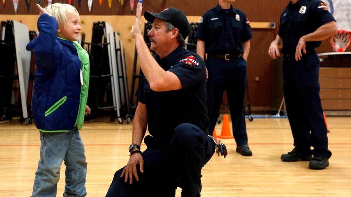 Richland Fire Department Capt. Dean Reents gets a high-five Tuesday from kindergartner Dominic Souza as he tries on a new jacket as part of Operation Warm, a national program, at Jefferson Elementary School in Richland. This is the third year that the Richland Fire Department has worked with Goodwill and community members to raise money to buy warm coats for kids at Richland elementary schools.