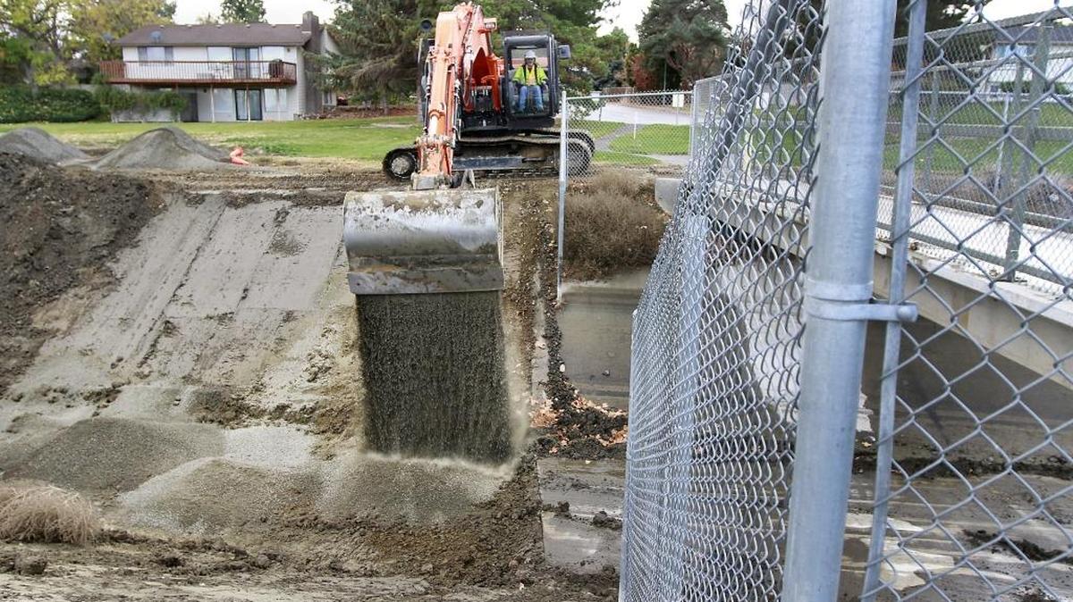 A Kennewick Irrigation District worker operates an excavator Monday near a concrete foot bridge over the Division 4 canal near Creekstone Drive.