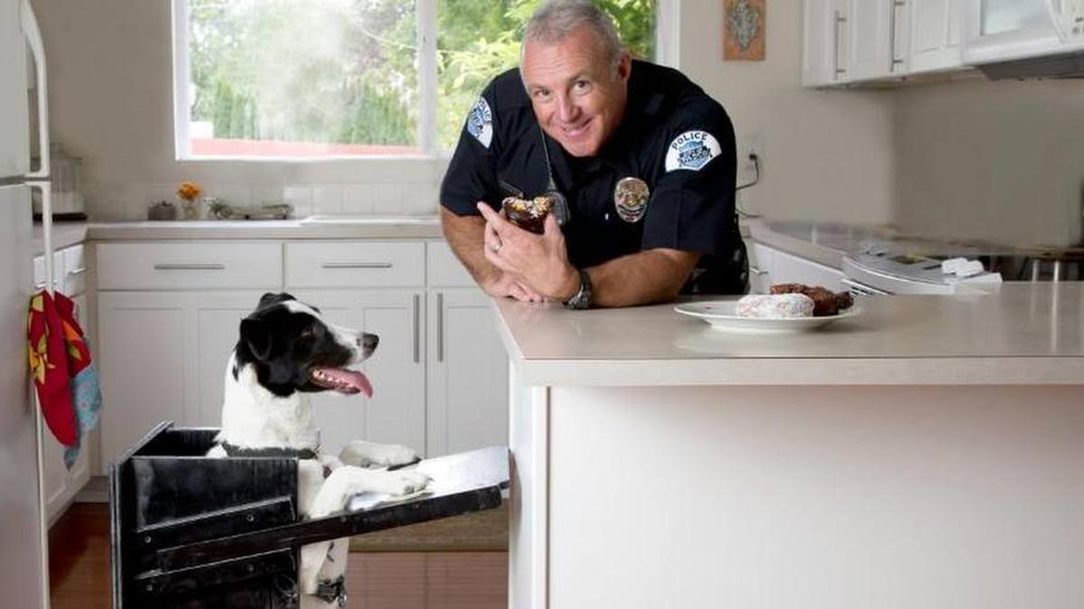 Pasco police Officer Mike Nelson feeds a dog in a picture for the calendar.