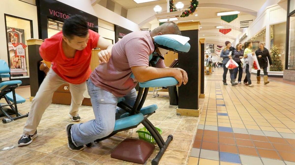 Holiday shopper Daniel Campos of Moses Lake takes a break from his Black Friday bargain hunting to get a massage at Columbia Center mall in Kennewick. His masseur is John Smith at the Oriental Massage kiosk in the center of the building.