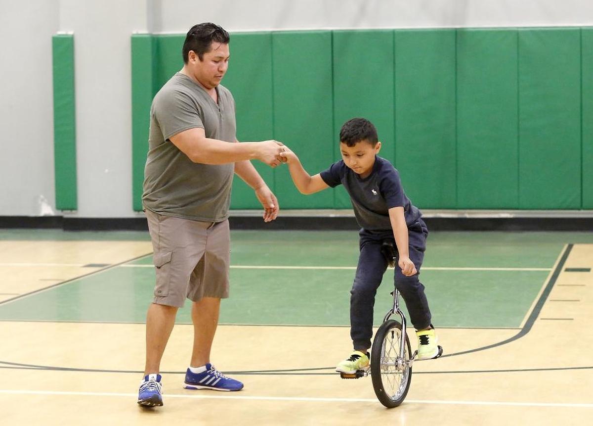 Circus performer Walter Chimal of Pasco helps Aaron Mendoza, 8, one of his his after-school program students at Tierra Vida recreation center, make a safe turn on a unicyle in the recreation center of the Pasco apartment complex. The Chimal family has long tradition of circus performers starting with their grandfather who ran away as a youngster to join the circus.