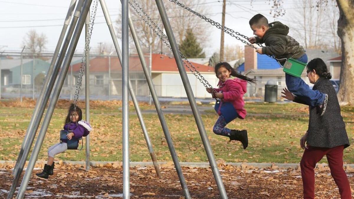 Luisa Chavez of Pasco scampers behind her three children Thursday afternoon in a effort to keep their momentum going while playing under sunny skies on the swings at Pasco’s Memorial Park. From left, they are Sinai, 3, Aileen, 5, and Carlos, 8. Today’s forecast is for partly sunny skies with a high temperature around 40.