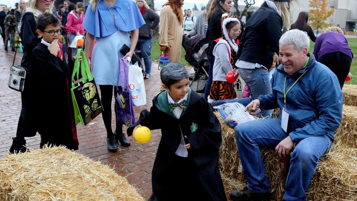 Stan Johnson, parks and recreation coordinator with the city of Richland, looks on as Samuel Solorio, 6 of Kennewick, dressed as Draco Malfoy, throws a ball while bowling during the fall carnival at John Dam Plaza in Richland. With Samuel, at left, is his brother Jesus, 8, as Harry Potter, his sister Isabel, 12, as Luna Lovegood and his mother, Noelle, as Fleur Delacour.