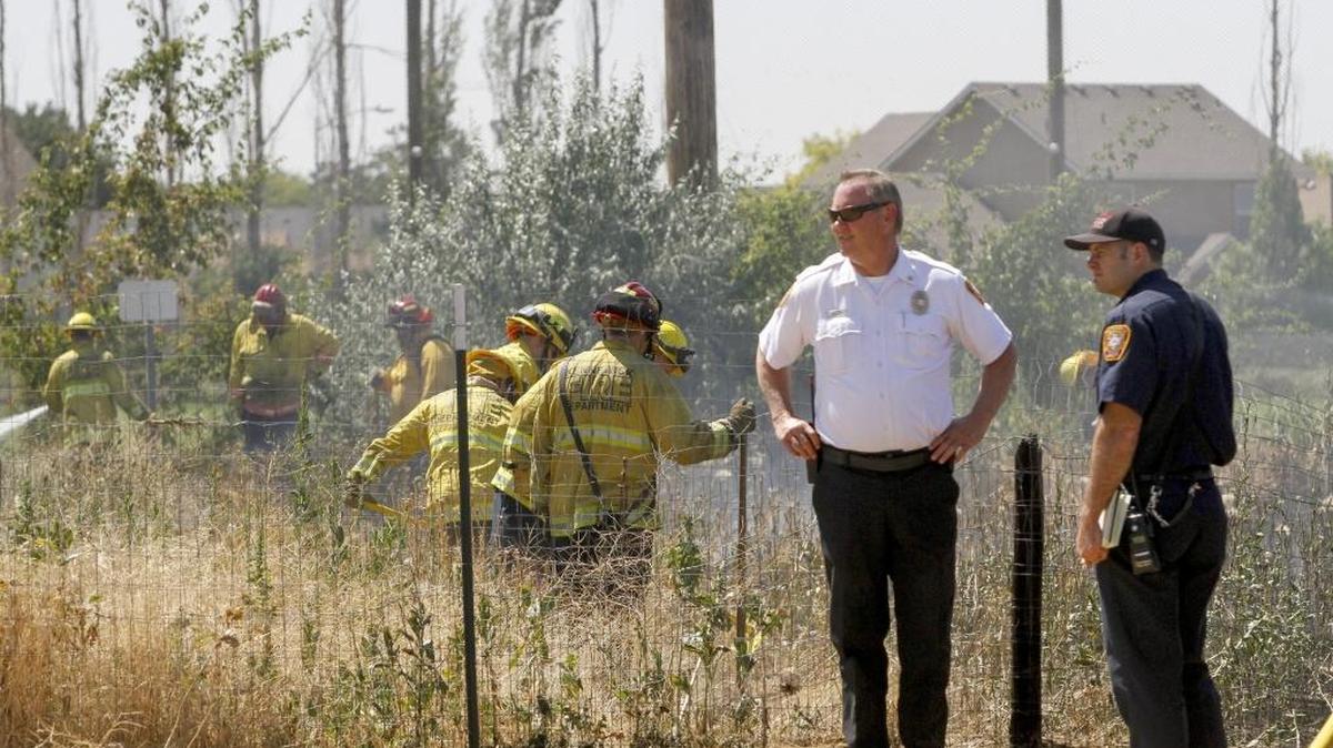 Firefighters from Kennewick and Benton County Fire District #1 work to put out a natural cover field fire Thursday behind the fourplexes off Albany and McKinley. Police evacuated residents of the fourplexes as a precaution. There were no injuries or damage to homes.