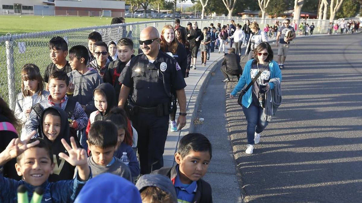 Pasco Police Officer Ray Aparicio joins Emerson Elementary School students, staff and parents Friday morning during their Walk to School safety event sponsored by Safe Kids Benton-Franklin and the Benton-Franklin Health District. The event is to raise awareness about pedestrian safety and promote creating safer routes for students walking and biking to school. Watch a video at tricityherald.com/video.