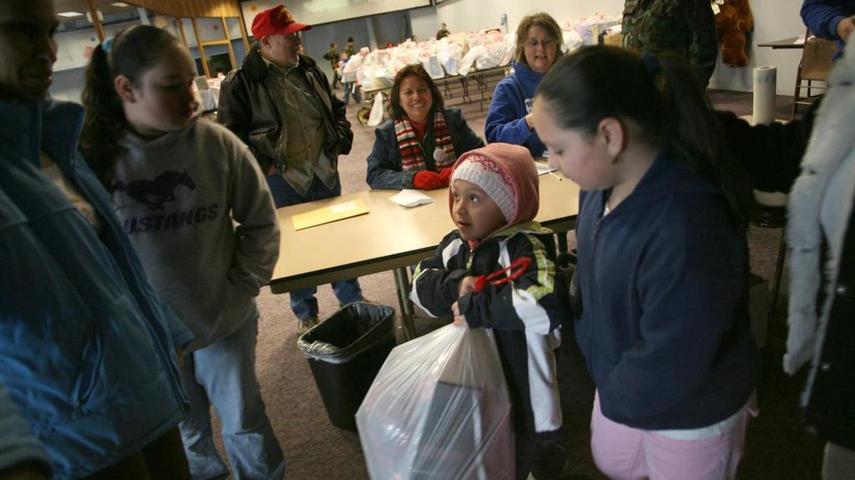 Lizette Alvarez looks at her mother, Cipriana Chavez, before stealing a glimpse of presents her family received from Marine Corps Reserve Toys for Tots in Pasco in this file photo.