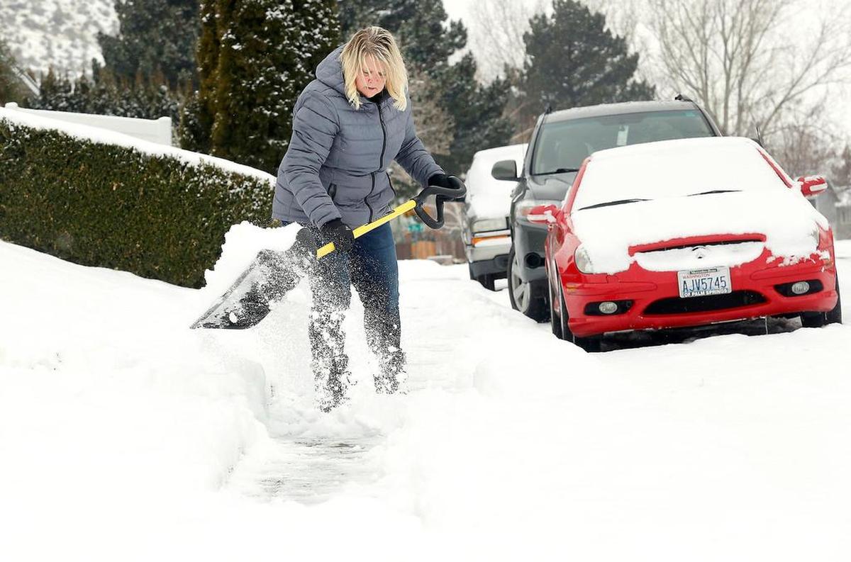 Suzanne Jaquish takes advantage of a lull in the snowfall Friday to shovel her driveway and sidewalk in front of her home on West 20th Avenue in Kennewick.