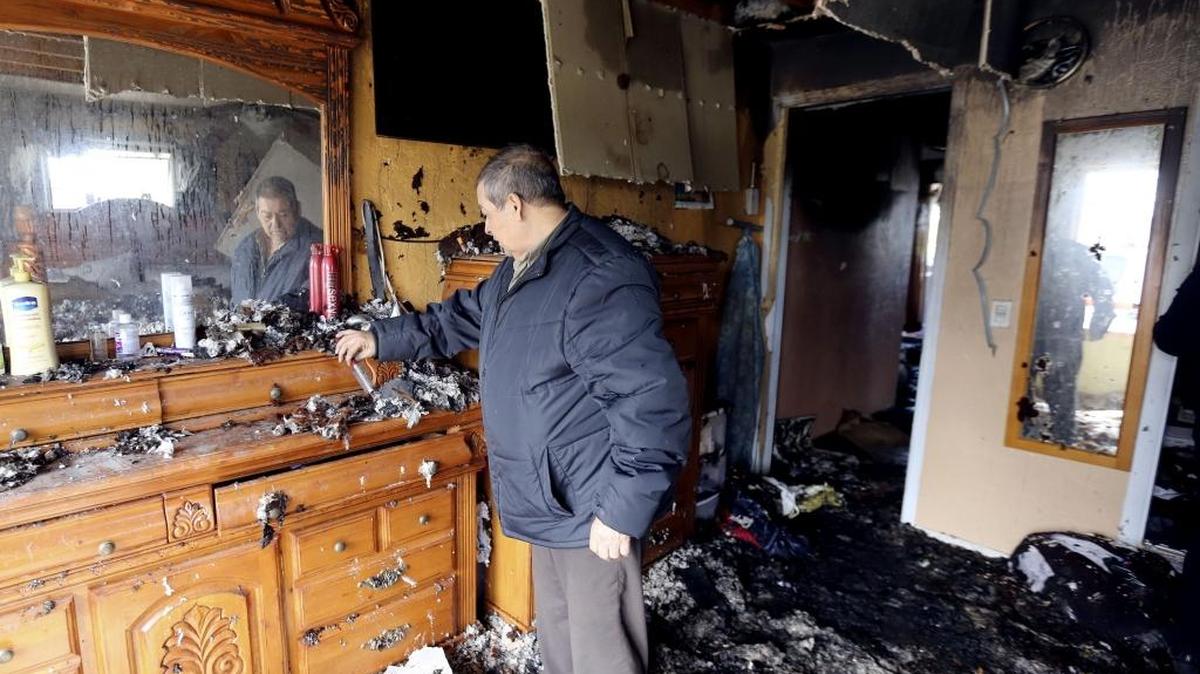 Ignacio Ayala of Kennewick cleans off his dresser Friday morning following an electrical fire that left his home badly damaged. Family members were home at the time of the fire but no one was injured.
