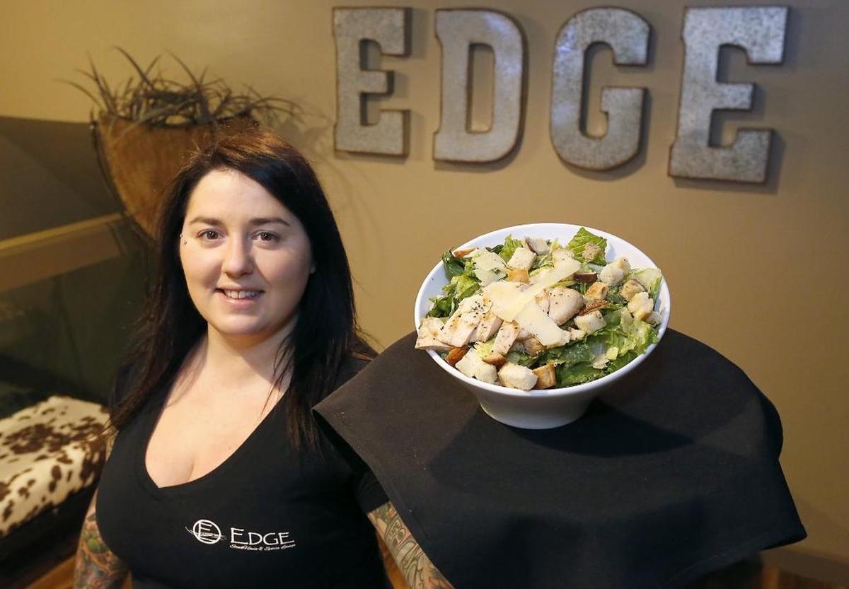 Lounge server Emilie Sahm holds a chicken ceasar salad a patron orders for lunch at the new Edge Steak House & Sports Lounge in Kennewick. The new business is located in the former Tri-City Country Club facility at 314 N. Underwood St. in Kennewick. Watch a video at: tricityherald.com/video