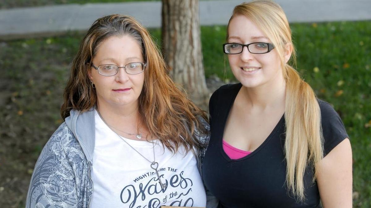 Sandra Thede, left, holds a photo of her brother, Jason Harris, as she stands next to her daughter, Olivia Harris, on Thursday.