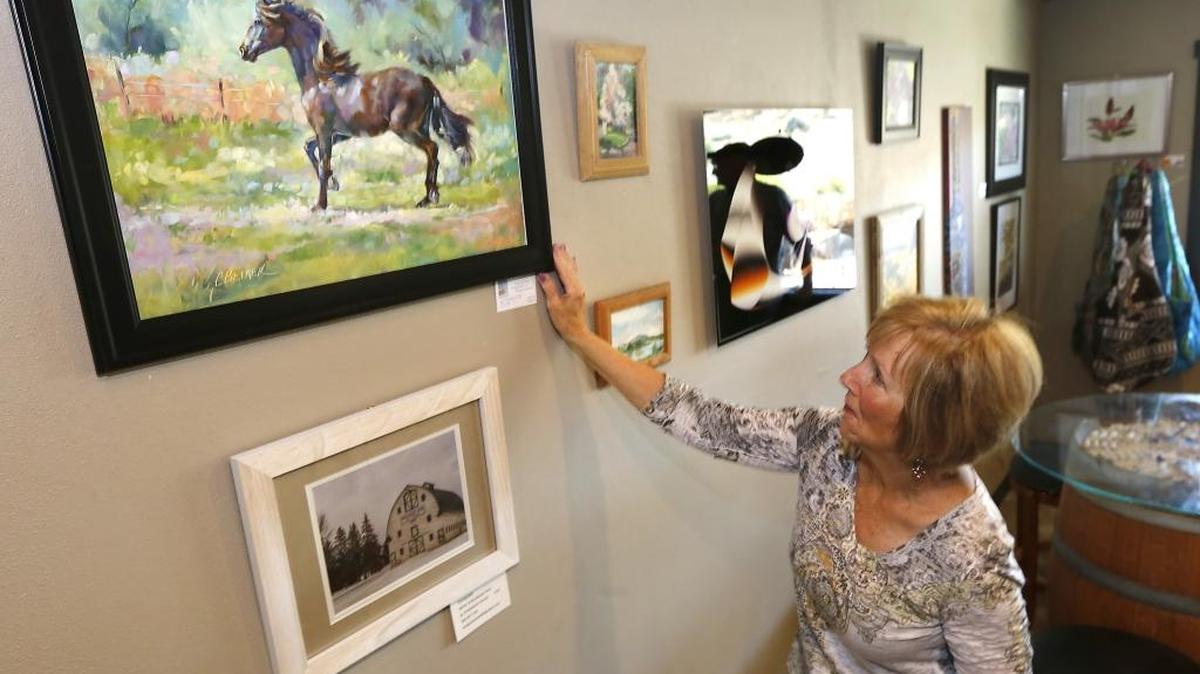 Kennewick artist Carol Betker adjusts her painting Monday after hanging it for display at Tucannon Cellars. Betker is part of the Cyber Art 509 online artist cooperative exhibiting work at the Benton City venue.