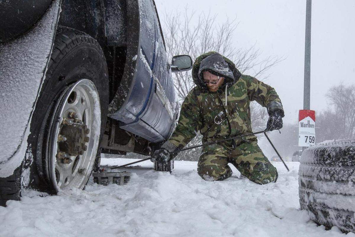 Jerry Dauder of Richland fixes a flat tire on his Chevrolet truck outside of a Circle K near George Washington Way on Saturday during the snow storm. The National Weather Service says there is a winter storm warning in affect until Sunday 1 p.m.