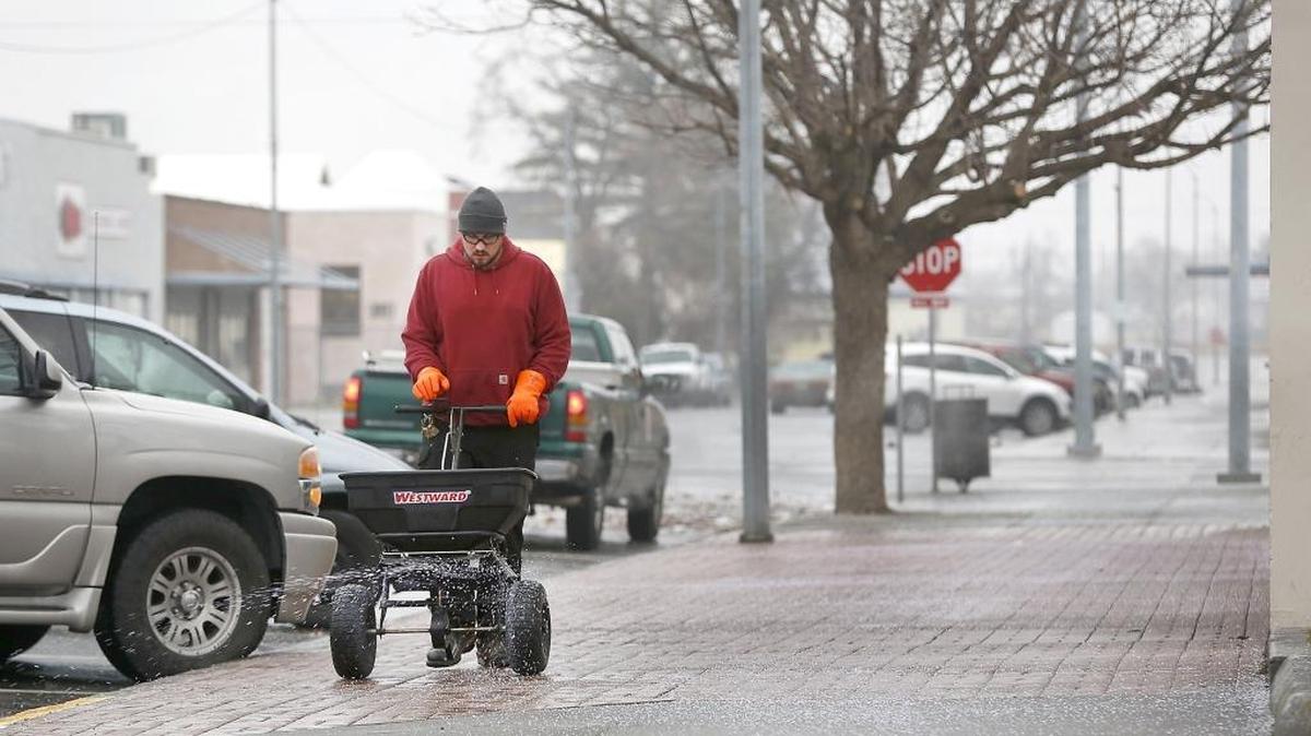A Franklin County employee, who declined to give his name, spreads granular ice melt Wednesday on the freezing rain encrusted sidewalk in front of a county building in the 400 block of West Clark Street in Pasco.