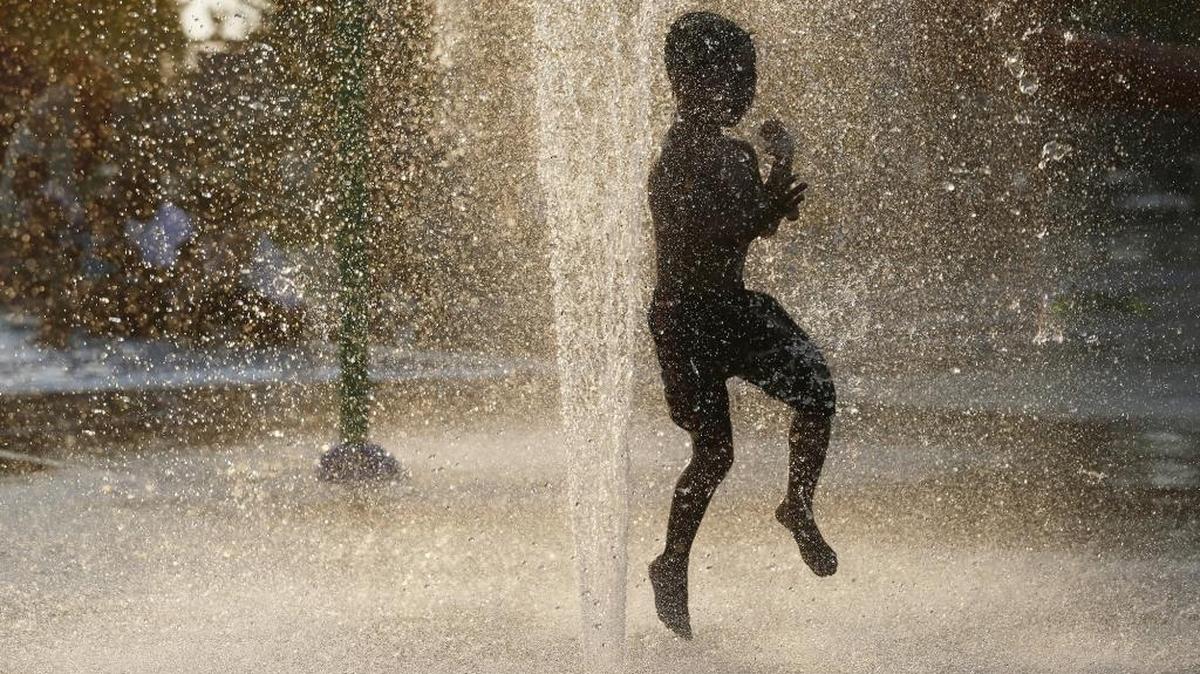 A boy jumps through a fountain in 2015 at the Memorial Park Pool in Pasco.
