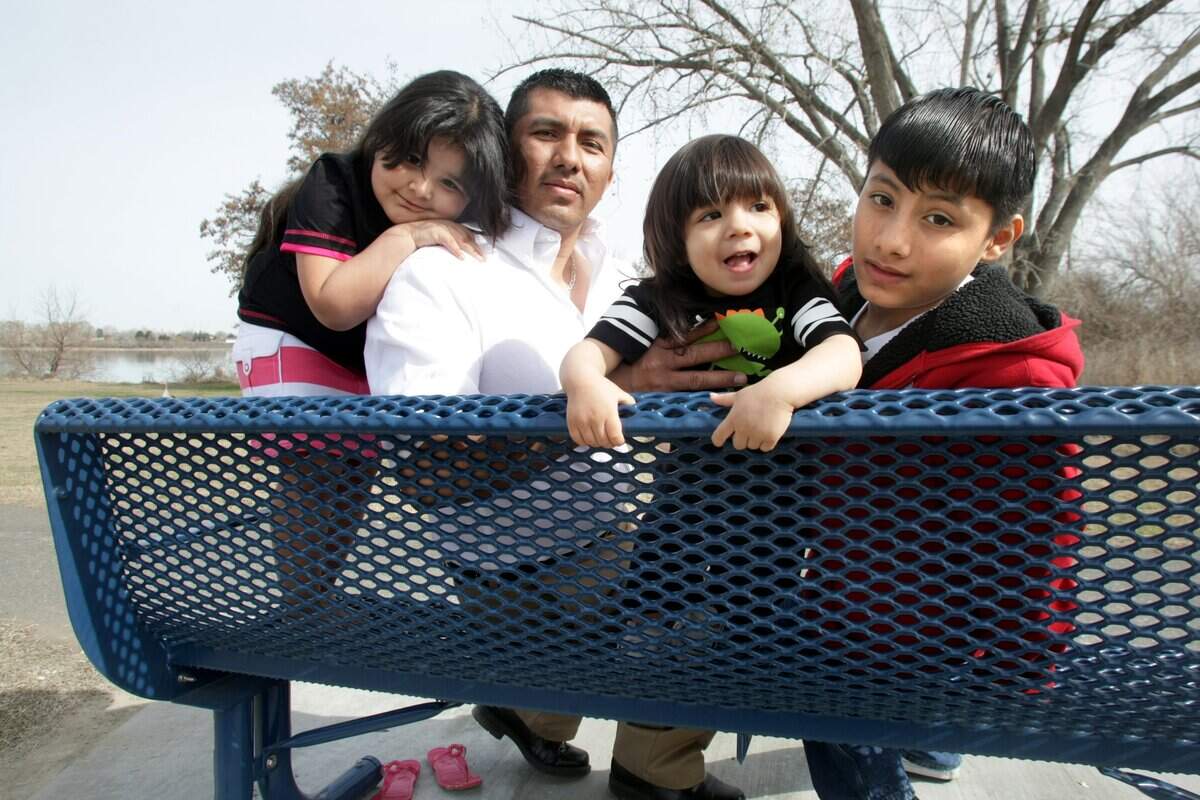 Juan Campos Gomez is surrounded by his three children during a visit to the park bench memorial in Kennewick's Columbia Park honoring his slain wife Araceli Gomez. The children, from left, are: Brenda, 4, Salvador, 1, and Juan "Carlos" 12.