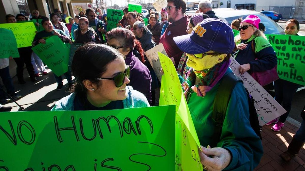 Yesenia Martinez, left, and Denny Rielly interact as more than 100 protestors gather Wednesday outside Rep. Dan Newhouse’s office in downtown Yakima.