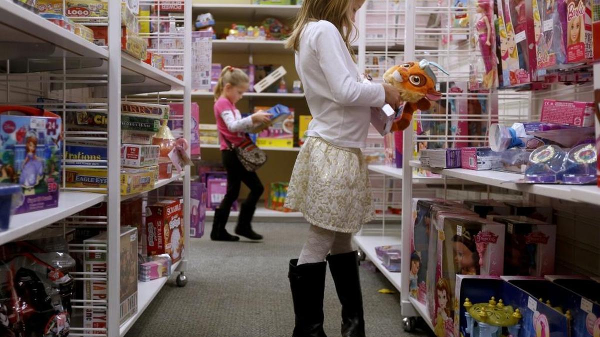Avery Bunger, 8, of Pasco, picks out a present for her cousin while her sister Addisyn, 5, plays with a toy in the background while doing last-minute Christmas shopping in 2015 with their mother Jami at Kohl’s in Richland.