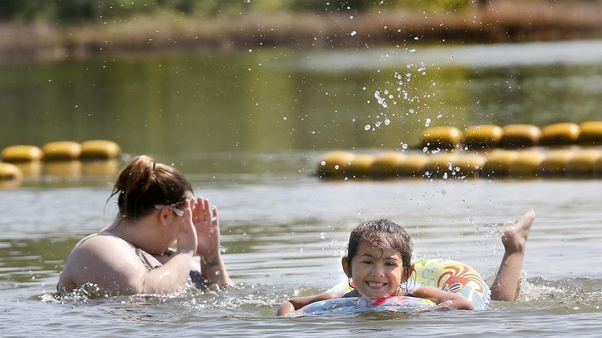 Ashley Ross shields her face as her daughter, Canndice Gutierrez, 5, propels herself towards shore Wednesday afternoon while swimming in the lagoon at Benton County’s Two Rivers Park in Finley. Warmer than normal temperatures are expected again Friday but a trough of low pressure with cooler temperatures and a slight chance of showers is expected to arrive from the Pacific in time for the weekend, according to forecasters. The two traveled from Connell with family friends to enjoy the sunny skies.