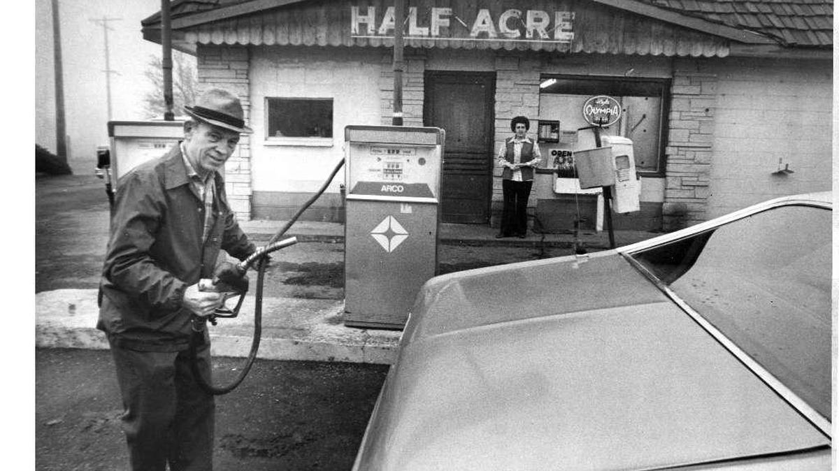 Al Meneely pumps gas at his Half-Acre grocery store in Finley while his wife watches. This photo was published in 1976.