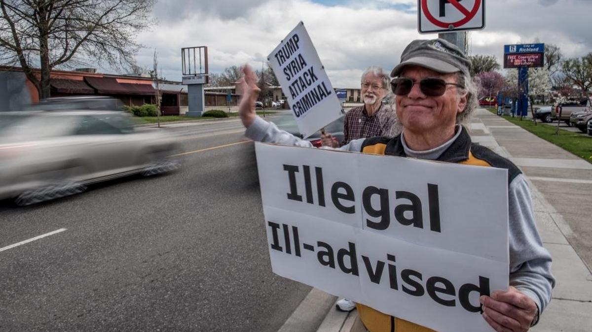 Gene Weisskopf (front) and Jim Stoffels of World Citizens for Peace hold signs protesting President Trump’s attack on Syria. The protest took place outside Richland City Hall along George Washington Way on Friday afternoon.