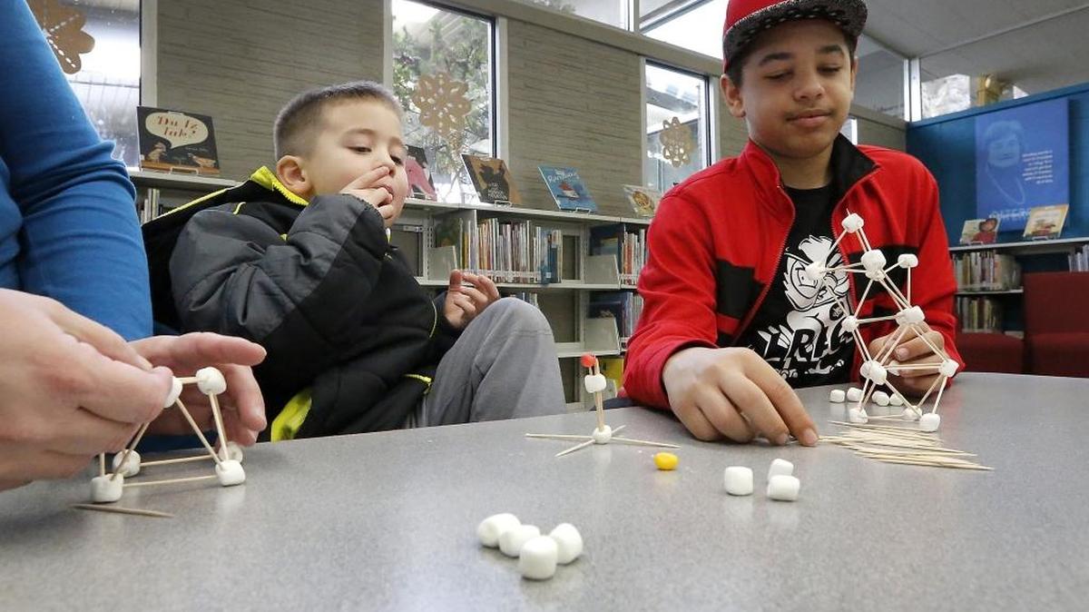 Elijah Garcia, 5, munches on part of his marshmallow and toothpick craft project Tuesday while his grandmother, Melody Florance, left, and brother, Tayven Kinsey, 12, work on theirs during the Warm Up With Cool Books winter break activity at the Mid-Columbia Libraries downtown Pasco branch. The three-day event, featuring stories, games, activities and special guests, is sponsored by Regional Service Corps in conjunction with Mid-Columbia Libraries and the Richland Public Library. The free event continues from 1-4 p.m. Dec. 28-29 at locations in Kennewick, Pasco and Richland. For more information, go to bit.ly/library_activity