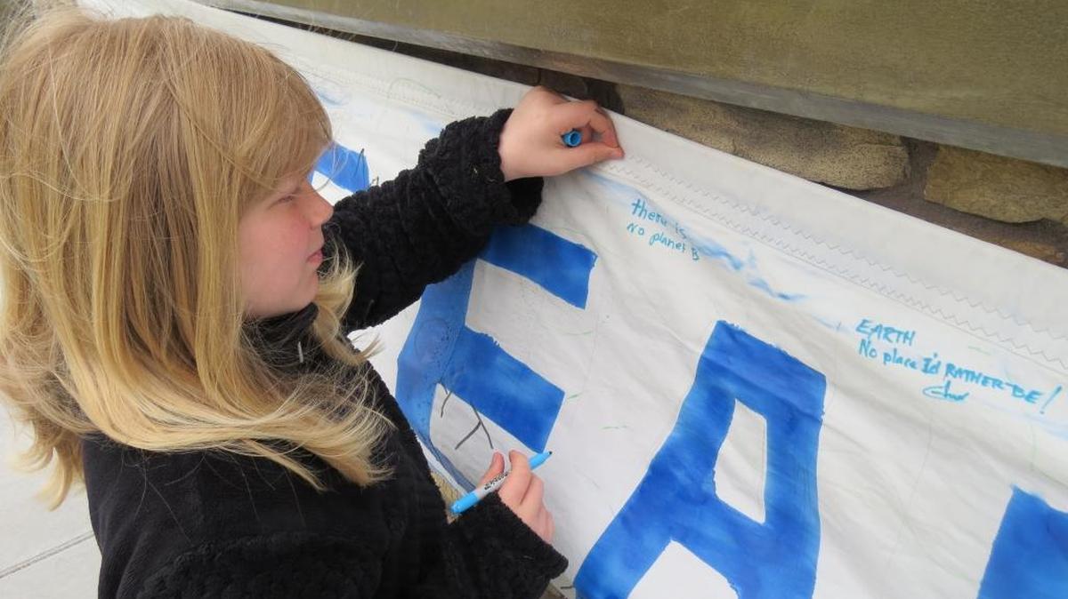 Wanda Vantine, 11, of Kennewick, signs a banner Saturday at the Peoples’ Climate Festival in Richland. “There is no planet B,” she wrote.