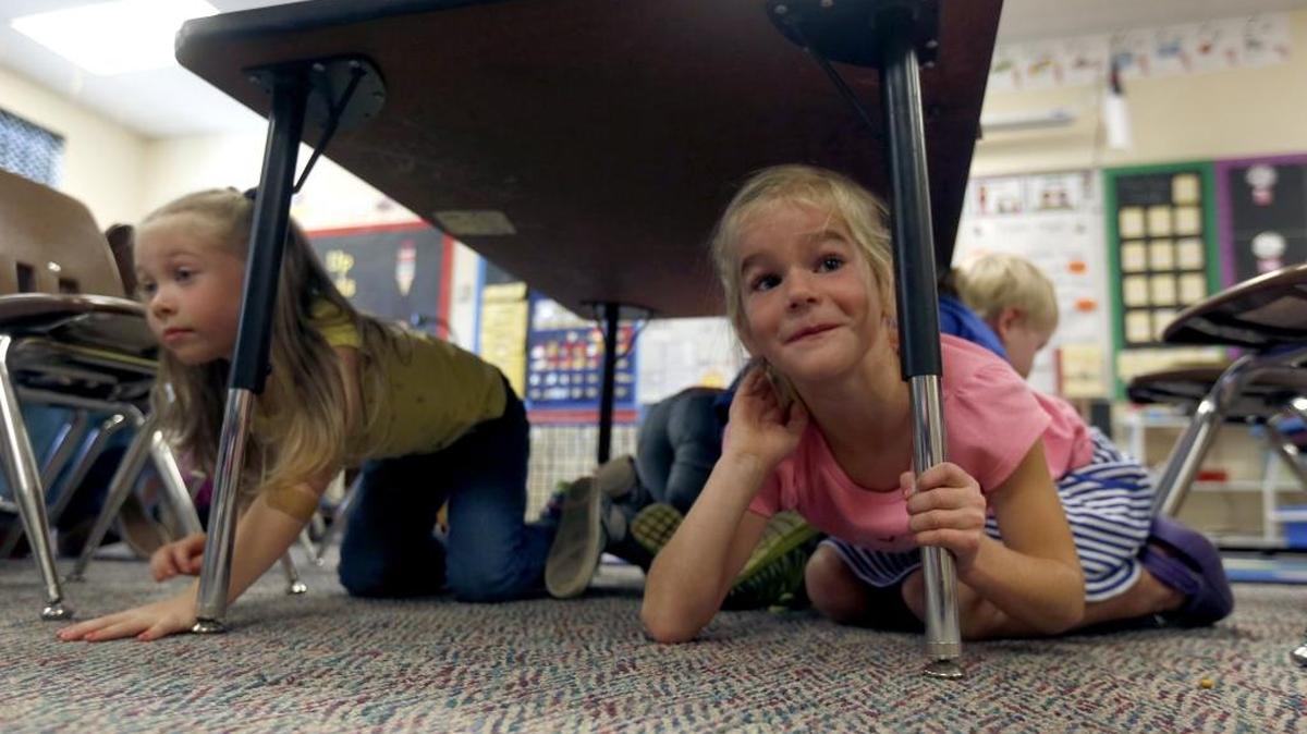 
Kindergarten students Abigail Larrick, right, and Charlotte Cox, left, hide under their desks Thursday as part of the Great Washington ShakeOut at Liberty Christian School in Richland. Schools and businesses in the area practiced “Drop, cover and hold on,” during a statewide emergency preparedness drill at 10:15 a.m.
