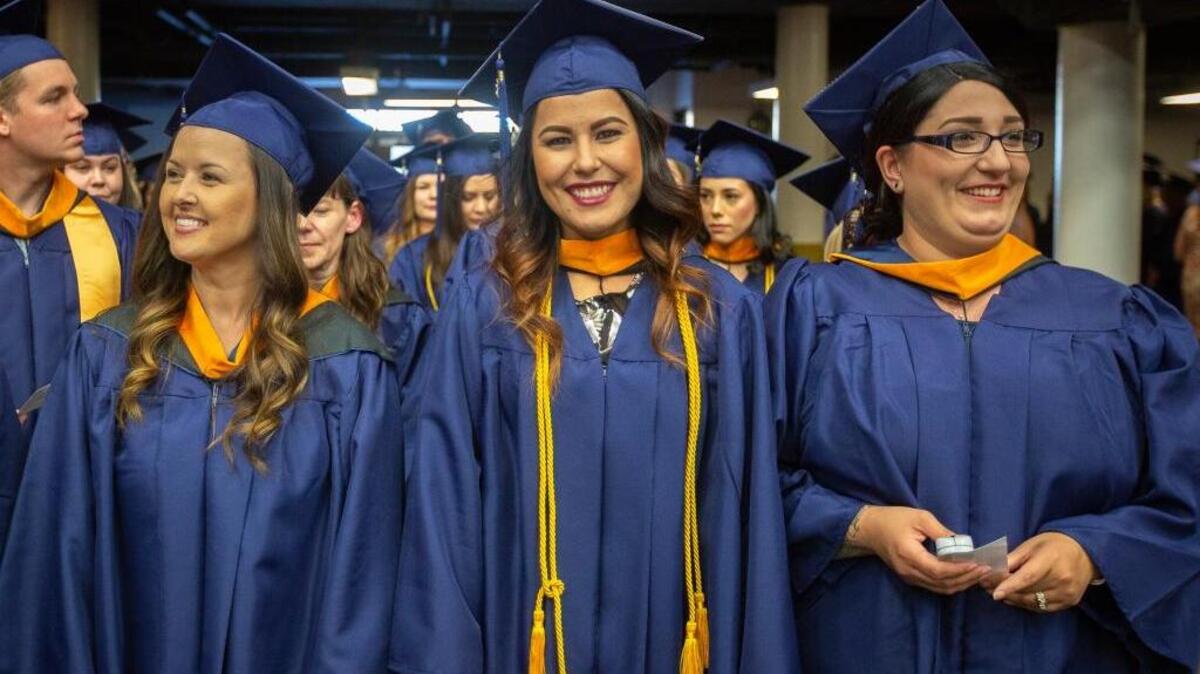 File photo - Classmates Adrianna Melo, left, Maria Mayorquin and Cassandra Asmussen smile as they look off to the crowd before they start walking for Columbia Basin College graduation ceremony at the Toyota Center in Kennewick last year.