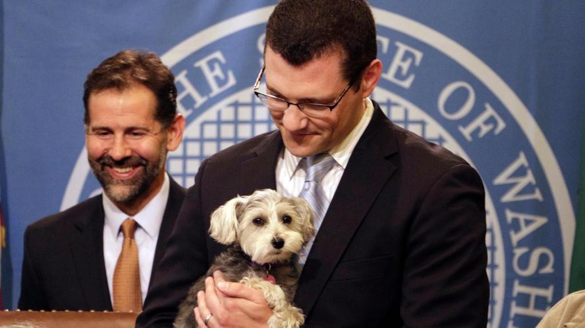 Sen. Joe Fain holds his dog, Waffles, as Gov. Jay Inslee signed in May a bill Fain sponsored that expanded the state's animal cruelty laws in Olympia. The measure makes it a civil offense to lock an animal in a car or enclosed space in dangerous conditions, like extreme heat or cold. The FBI will begin tracking cases of animal cruelty nationally in 2016.