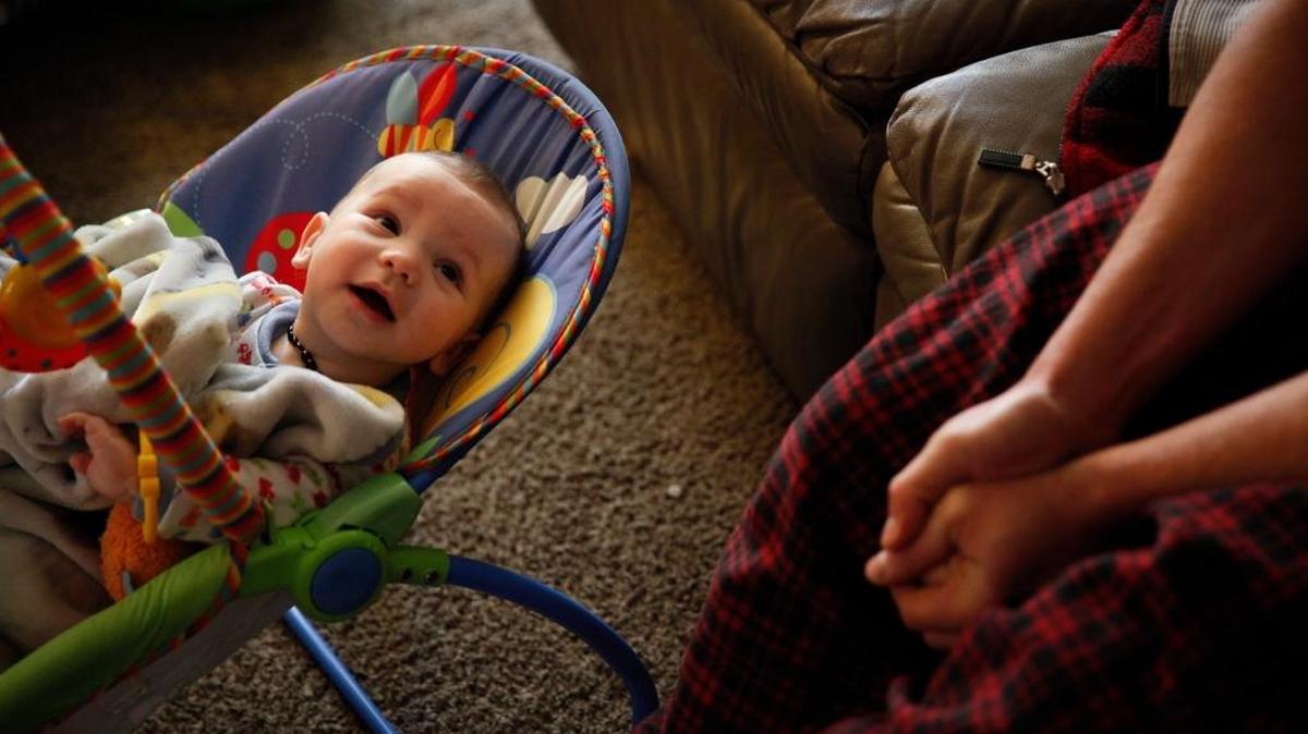 Charles White sits with his youngest son, Vaughn, 5 months, who tested high for levels of lead in Flint, Mich., . The drinking water may have exposed tens of thousands of people to lead and other toxic chemicals, but few see a way to pick up and move someplace safe.