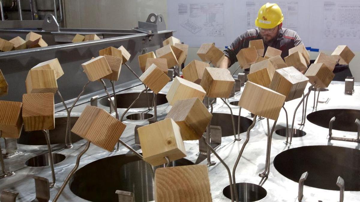 Vit Plant workers place wooden 4-by-4-inch blocks over steel rods as protection while they finish work on the glass-melter lids.