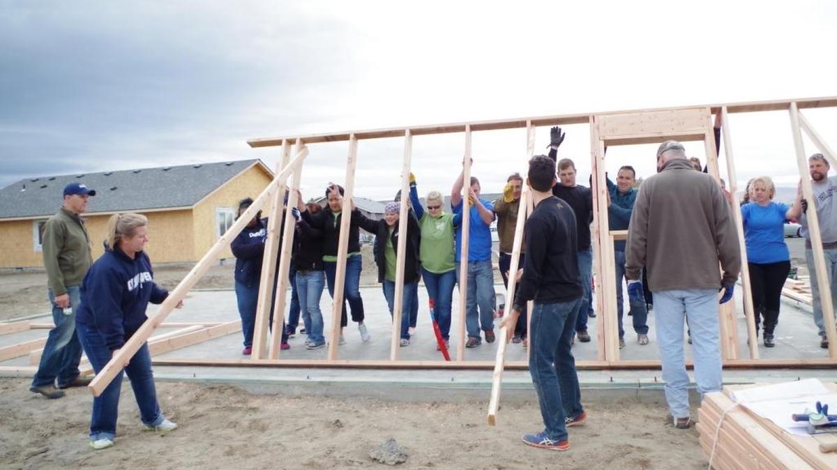A group raises a wall on a house that was sponsored by several insurance agencies from the community.