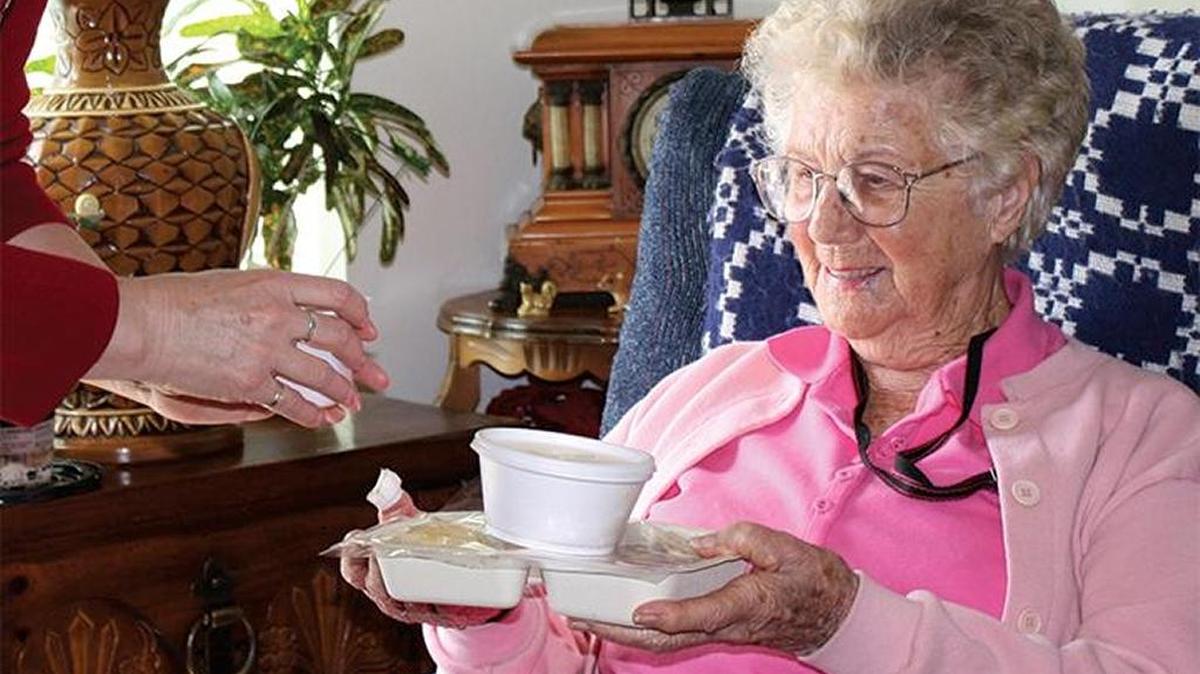 A client receives a warm meal delivered to her home thanks to Meals on Wheels.