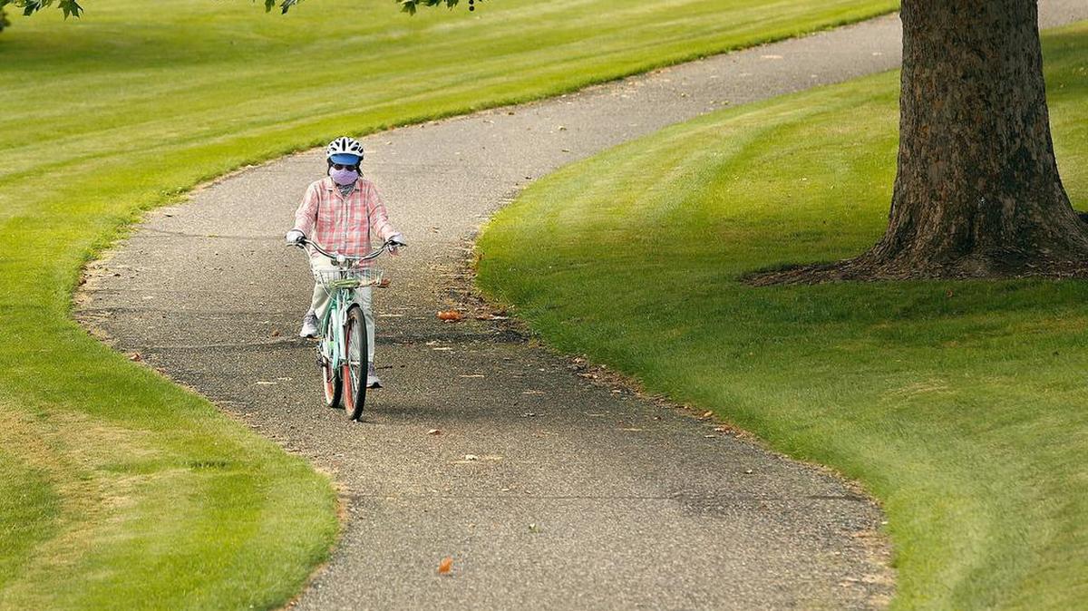 Shu-mei Li , 78, of Richland, wears a mask while pedaling away during her nearly daily bike ride along the paved pathway in Leslie Groves Park along the Columbia River in Richland. Visitors to the area can find many outdoor recreation opportunities.