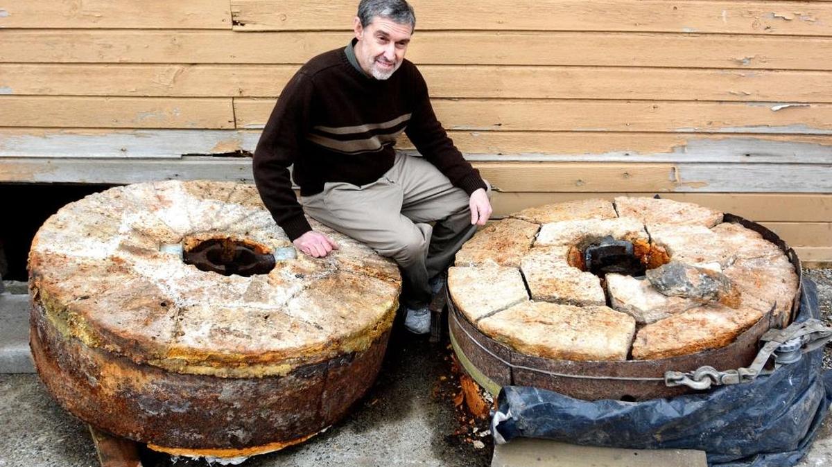 Pastor John Van Vogt sits with two giant, extremely heavy millstones unearthed from under the Pataha Flour Mills.