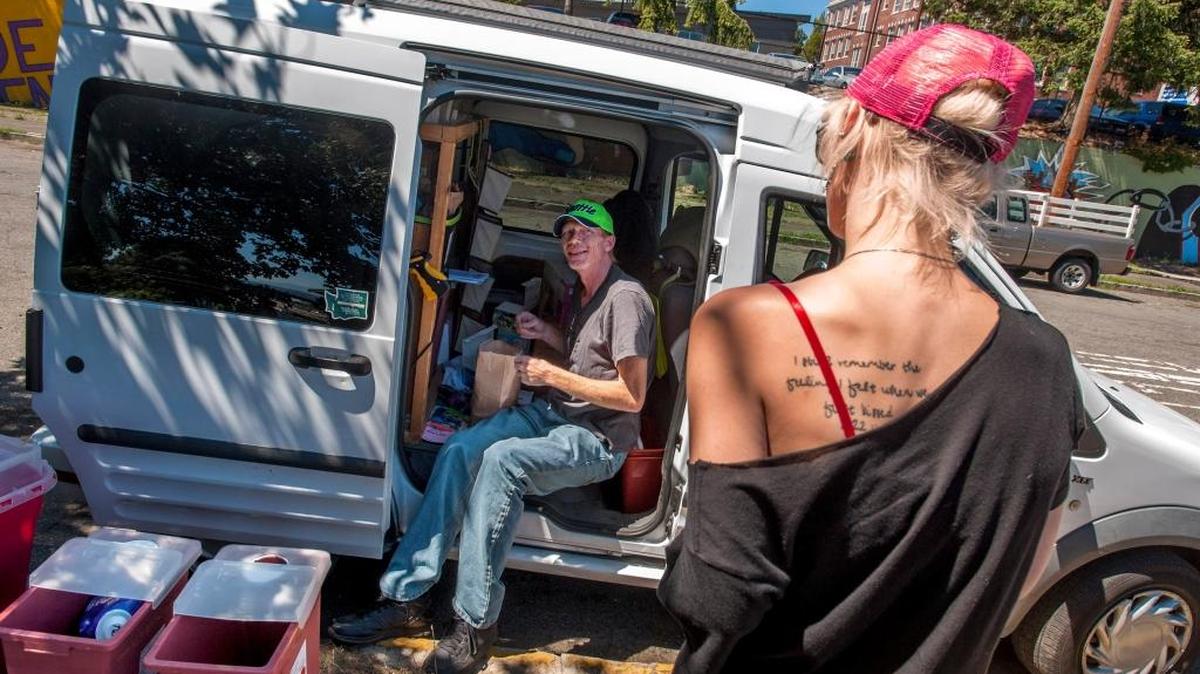 Community outreach worker Dennis Sayler of the Tacoma Needle Exchange offers Brianna Dawson new syringes for used ones, along with advice and other items to promote safe injecting. The exchange is now known as the Point Defiance AIDS project.