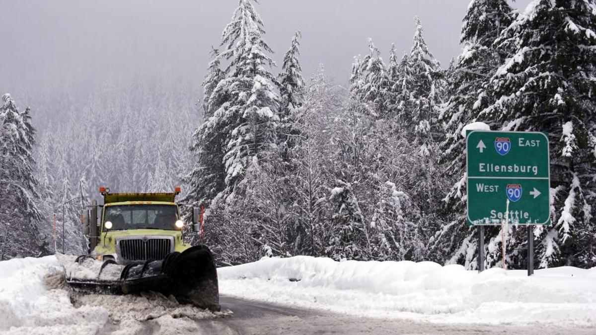 In this file photo, a snowplow clears an overpass of freshly fallen snow over Interstate 90 at Snoqualmie Pass, Wash. All Board Washington sees promise in a proposed Seattle-to-Pasco train route that would offer an alternate path over the pass. (AP Photo/Elaine Thompson, File)