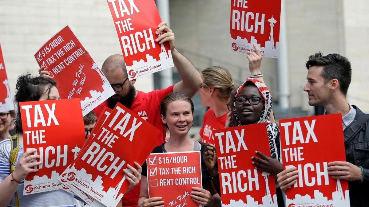 Demonstrators stand together as they wait for a Republican response to a new city income tax on the wealthy that was approved earlier by the Seattle City Council Monday, July 10, 2017, in Seattle. King County Superior Court judge John R. Ruhl on Wednesday ruled against Seattle’s new tax. His ruling likely will be appealed.