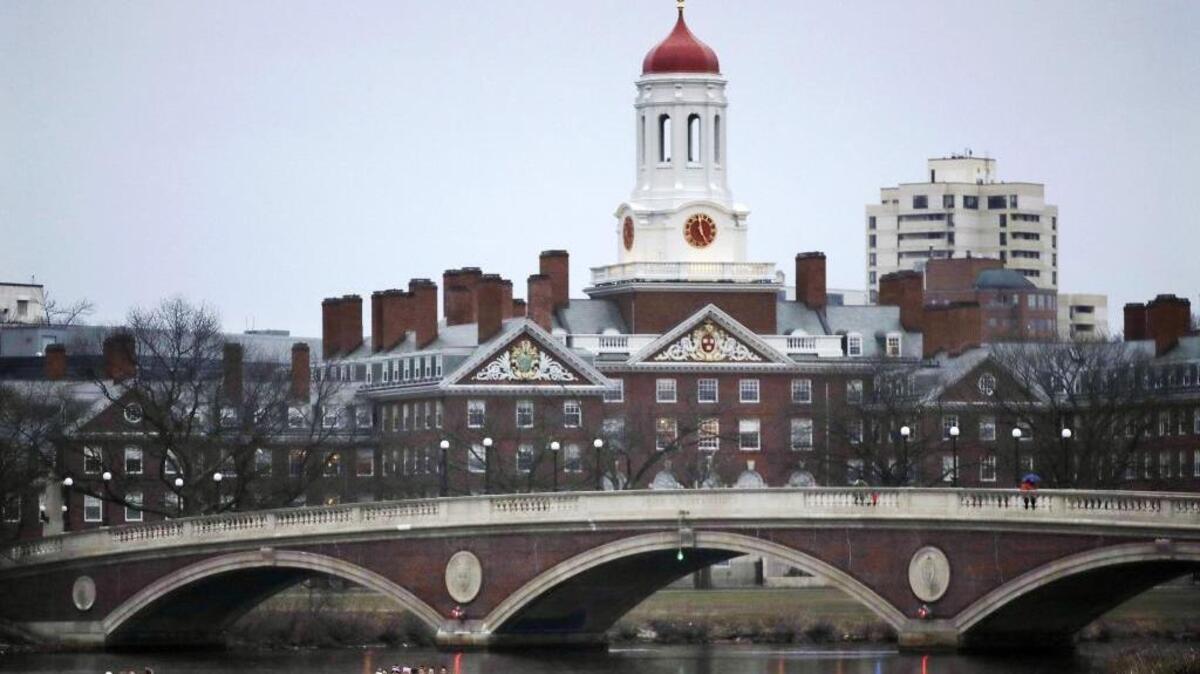 In this March 7, 2017 file photo, rowers paddle along the Charles River past the Harvard College campus in Cambridge, Mass. Harvard University will ban all student fraternities, sororities and single-gender clubs by 2022.