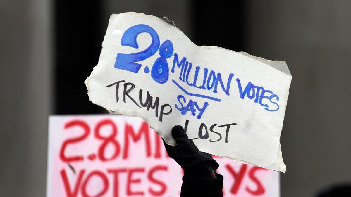Protesters hold signs outside the Capitol before Electoral College electors begin voting on Dec. 19 in Olympia, Wash.