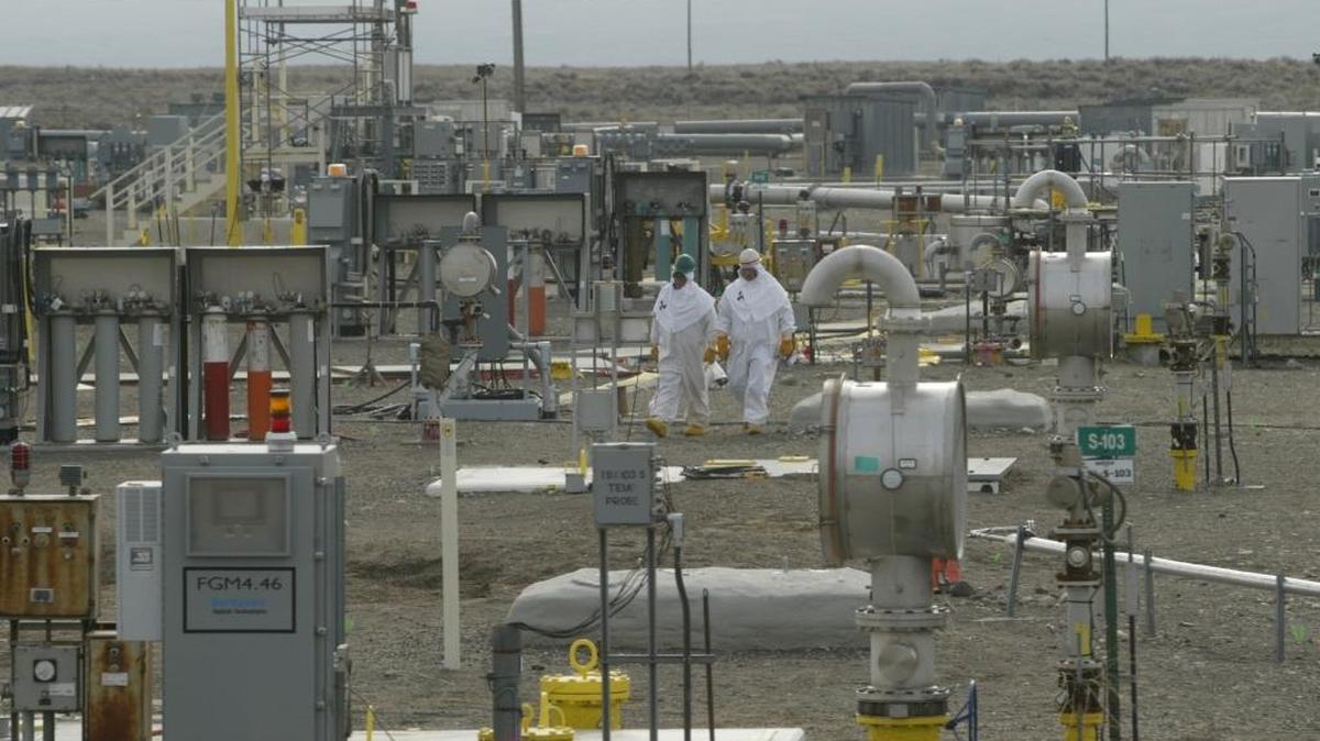 Employees dressed in protective suits walk through one of Hanford’s underground tank farms.